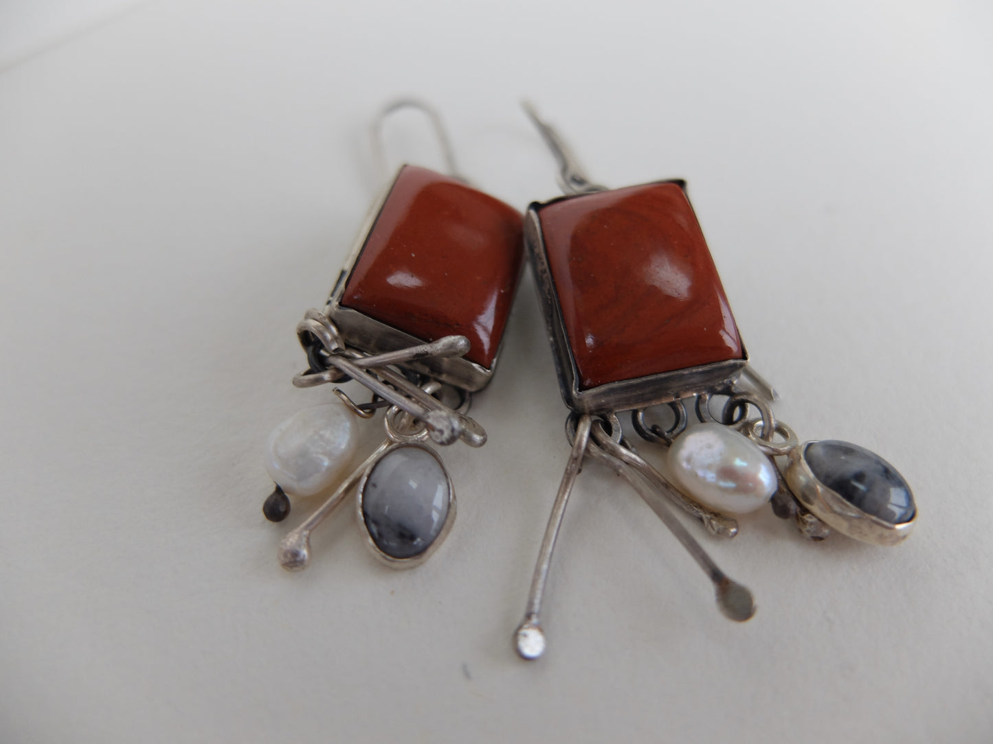 Pair of earrings with red stones and silver hooks on a light background