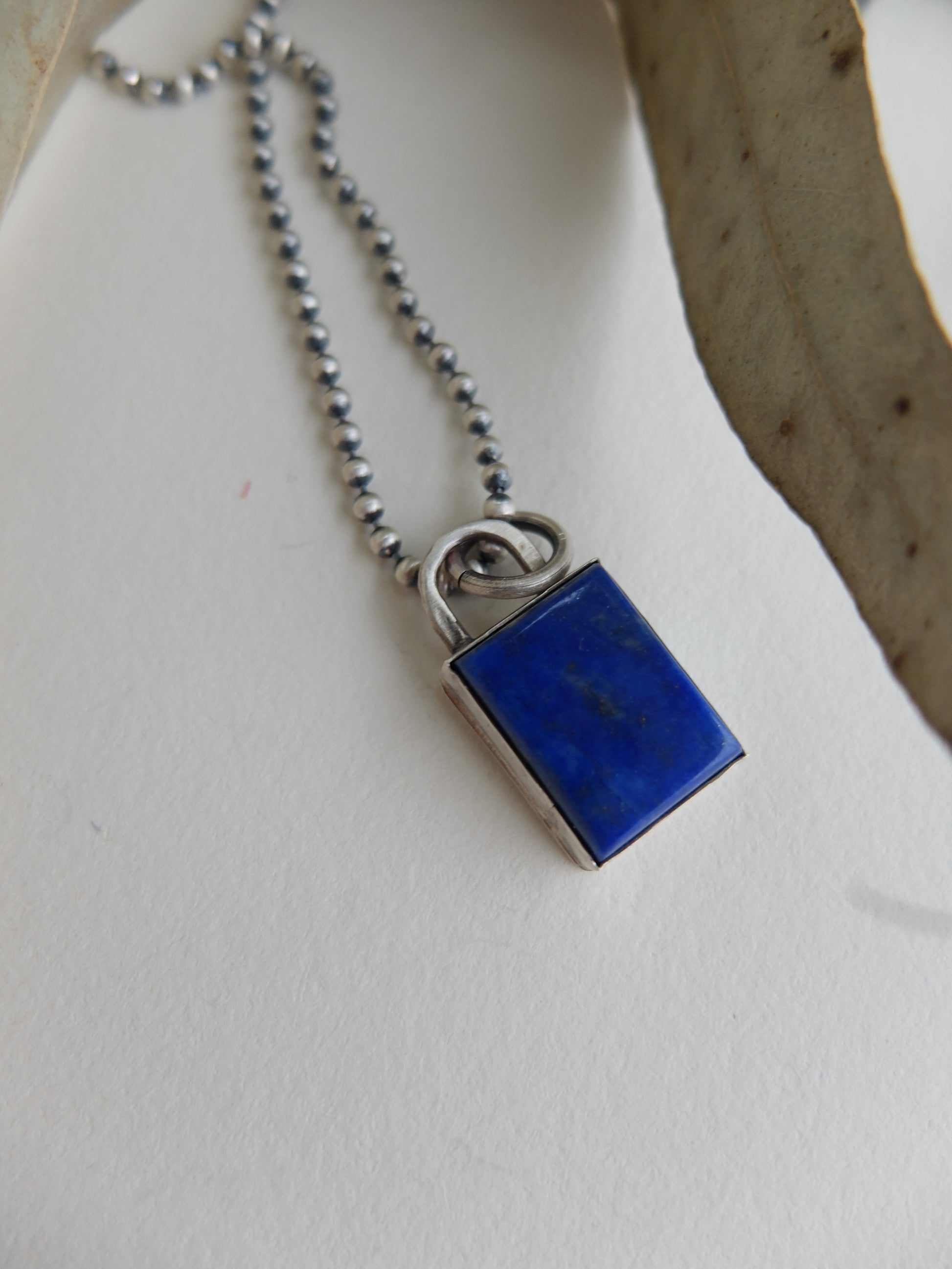 Blue pendant on a silver chain against a white background