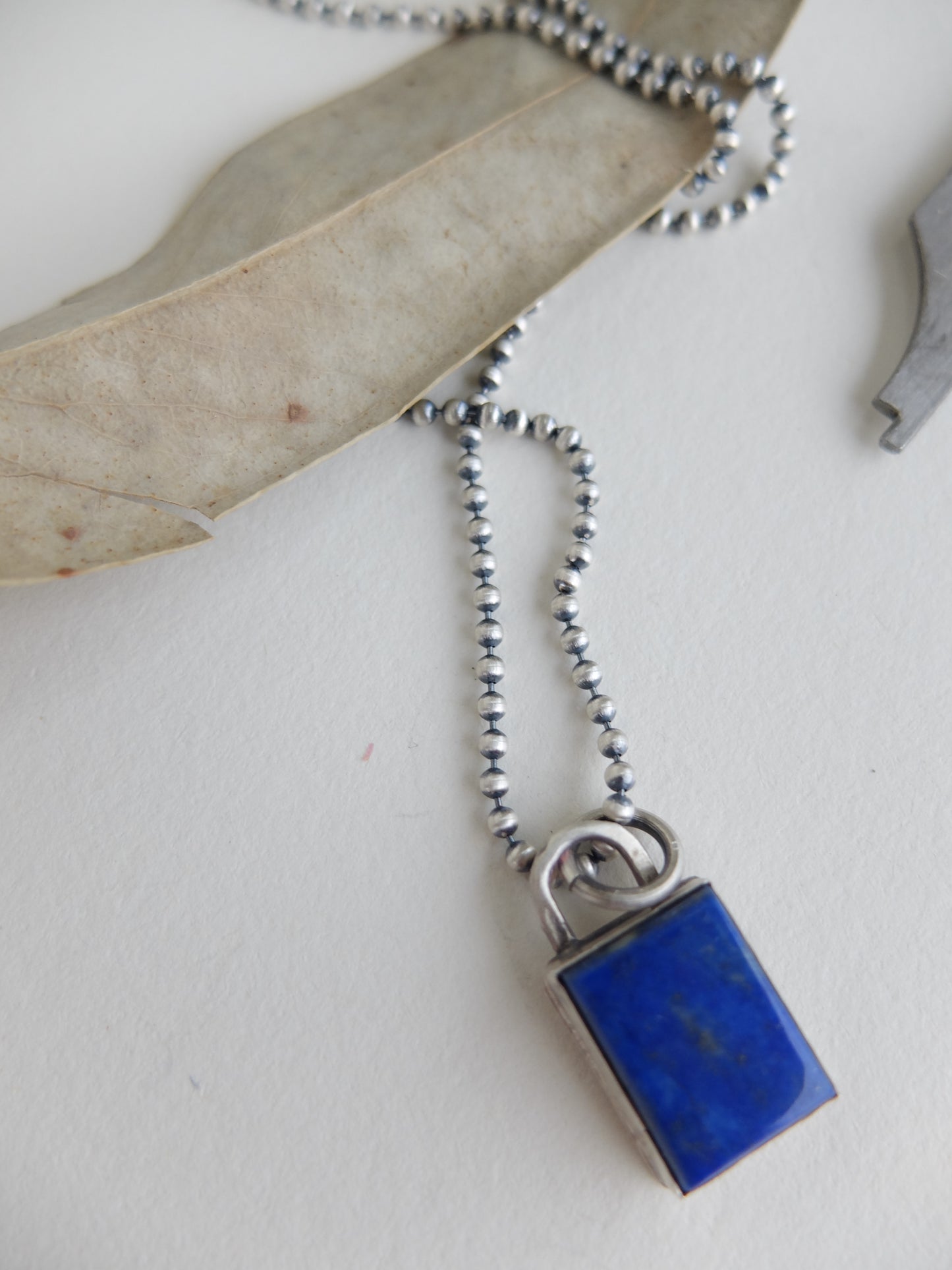Necklace with a blue pendant and silver chain on a white background
