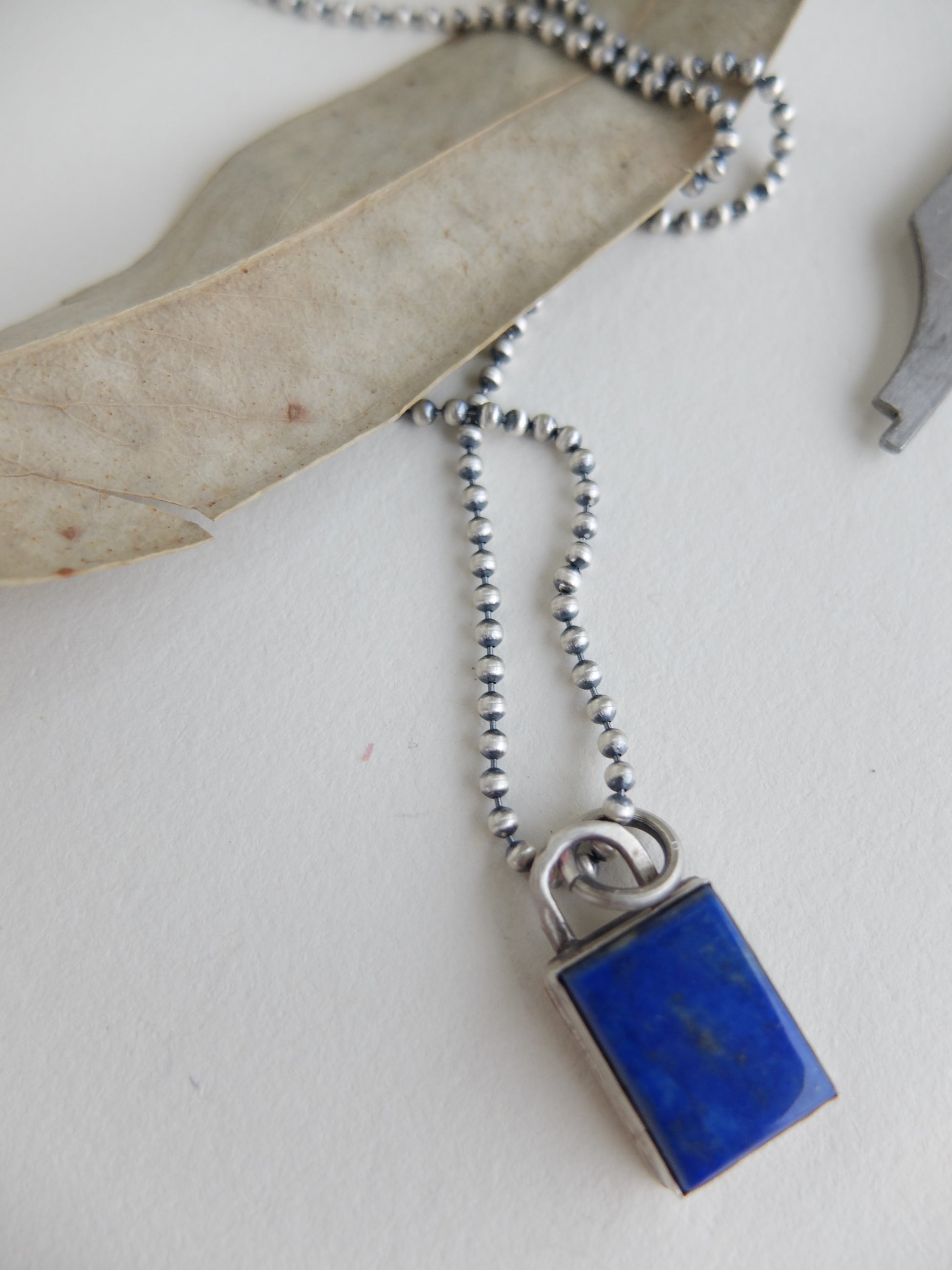 Necklace with a blue pendant and silver chain on a white background