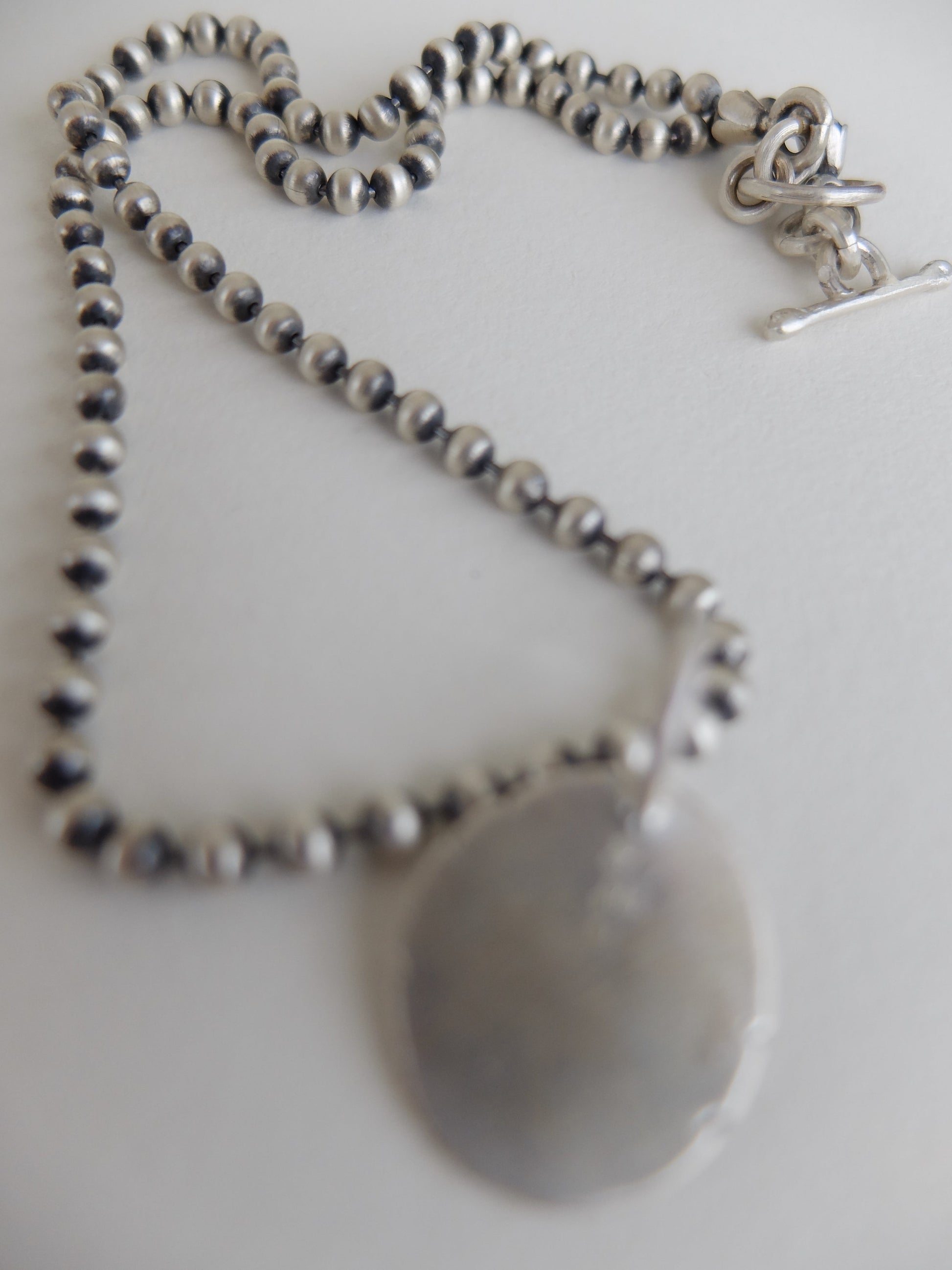 Silver Necklace with a round pendant on a light background