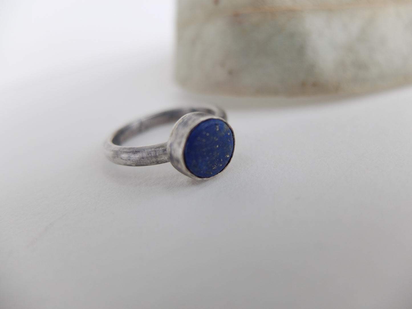 Silver ring with a blue stone on a white surface