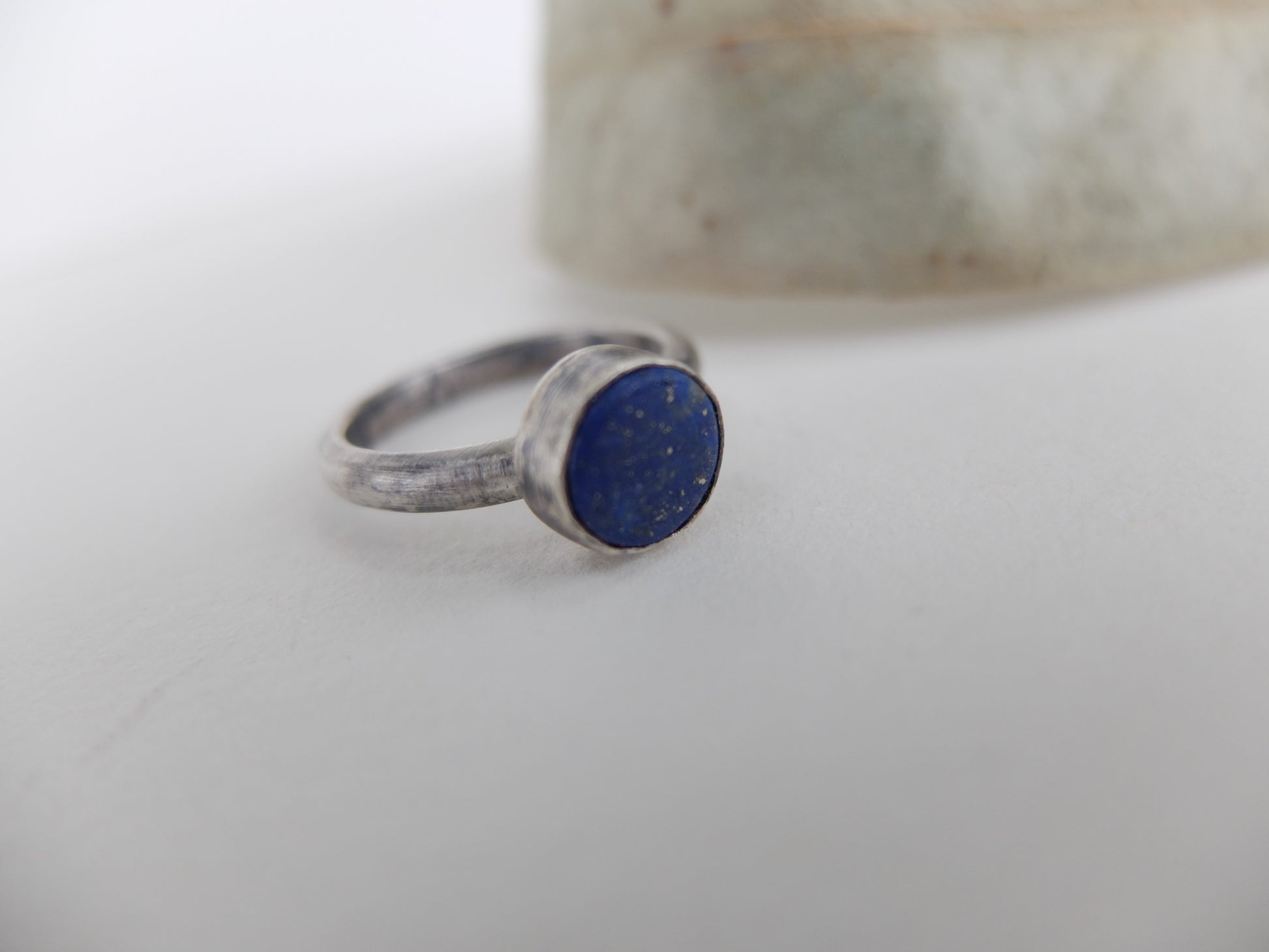 Silver ring with a blue stone on a white surface