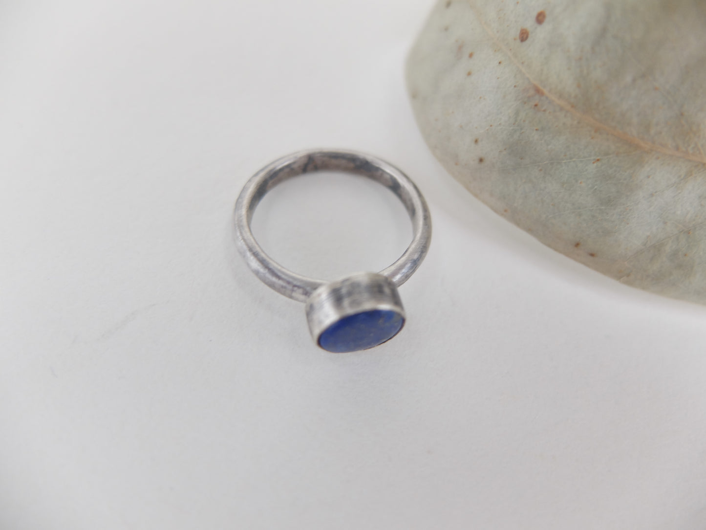 Silver ring with a blue lapis lazuli  stone on a light gray background