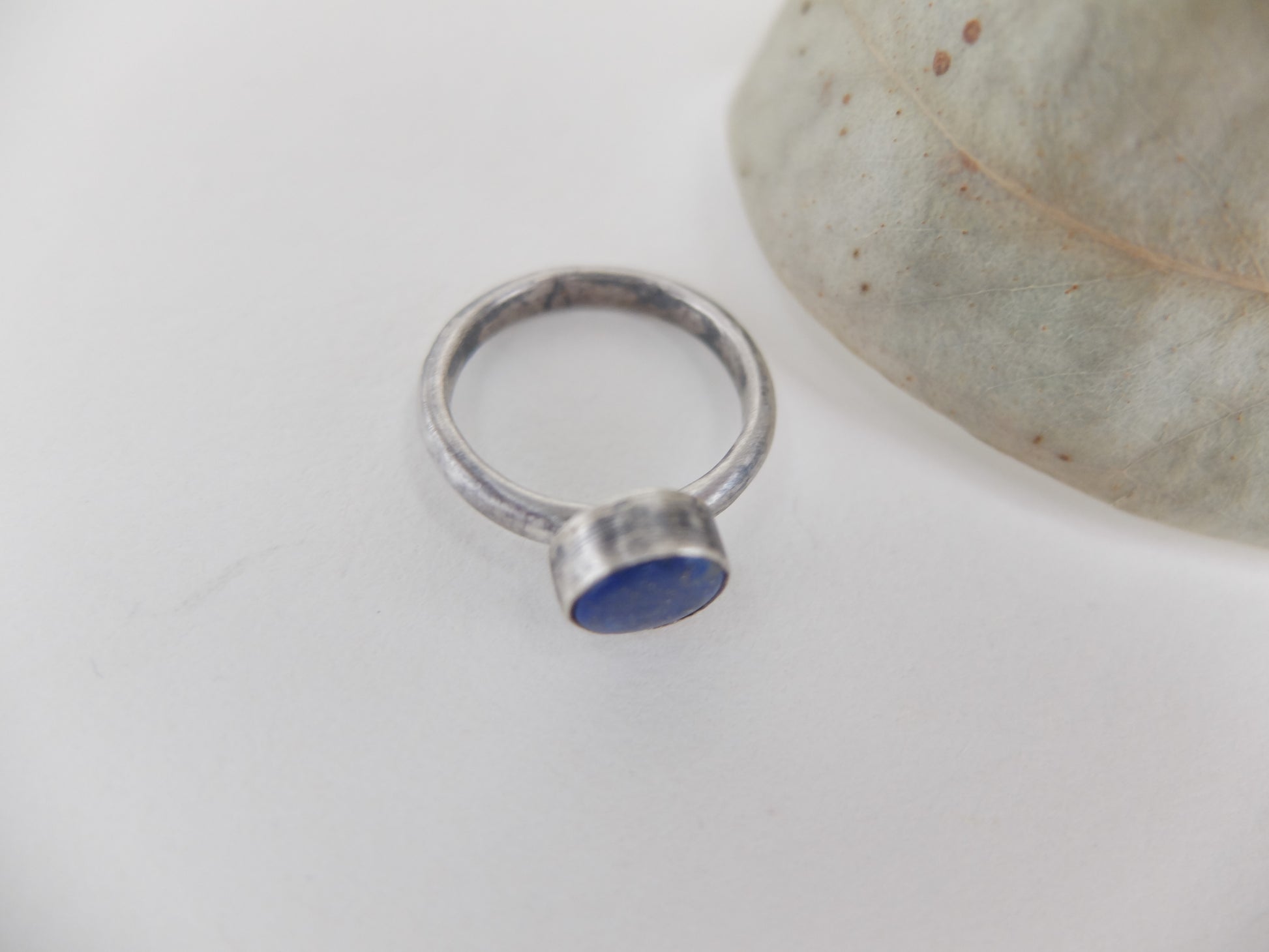 Silver ring with a blue lapis lazuli  stone on a light gray background