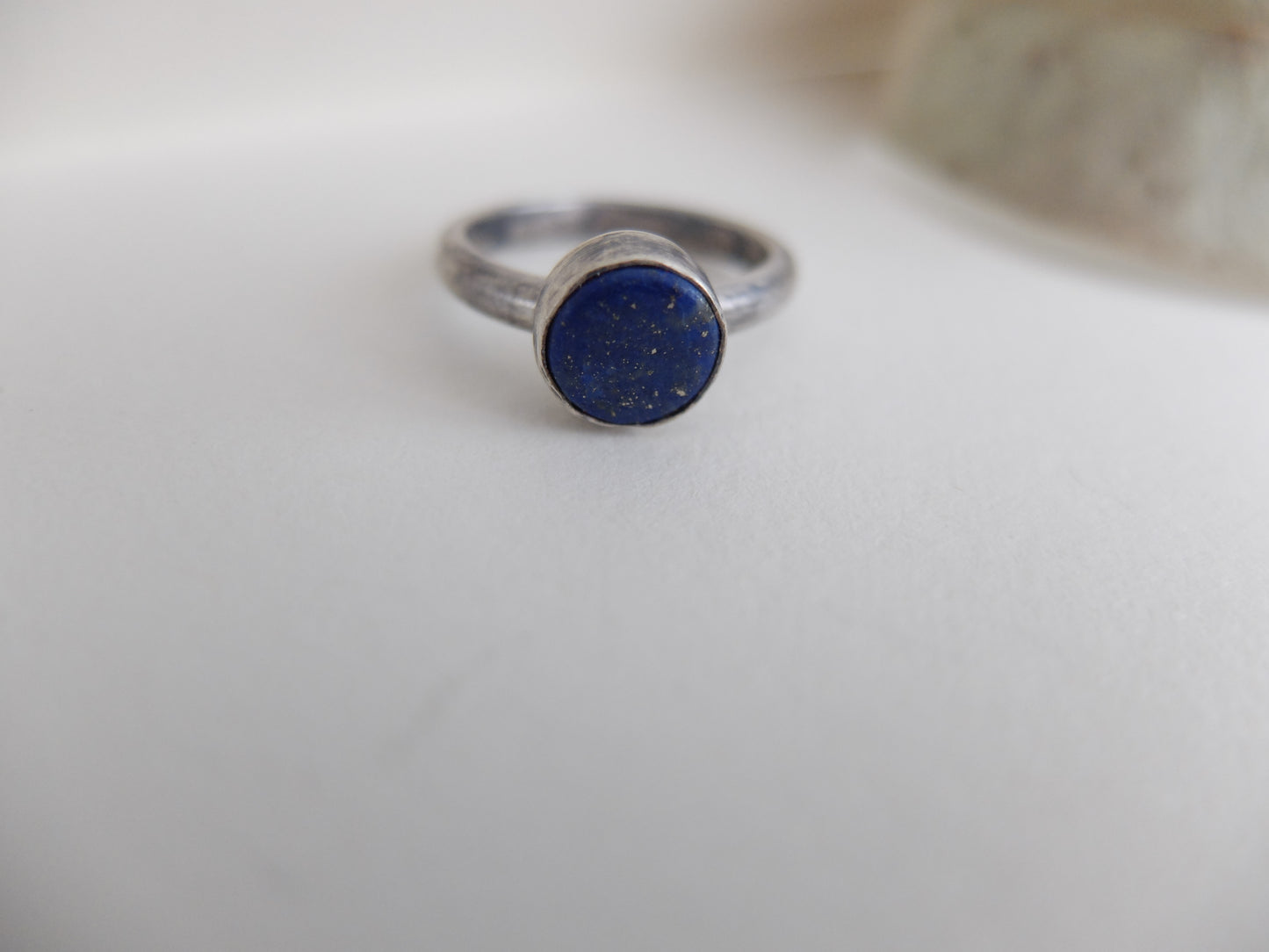 Silver ring with a blue stone on a white surface