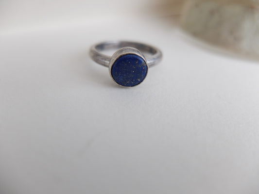 Silver ring with a blue stone on a white surface