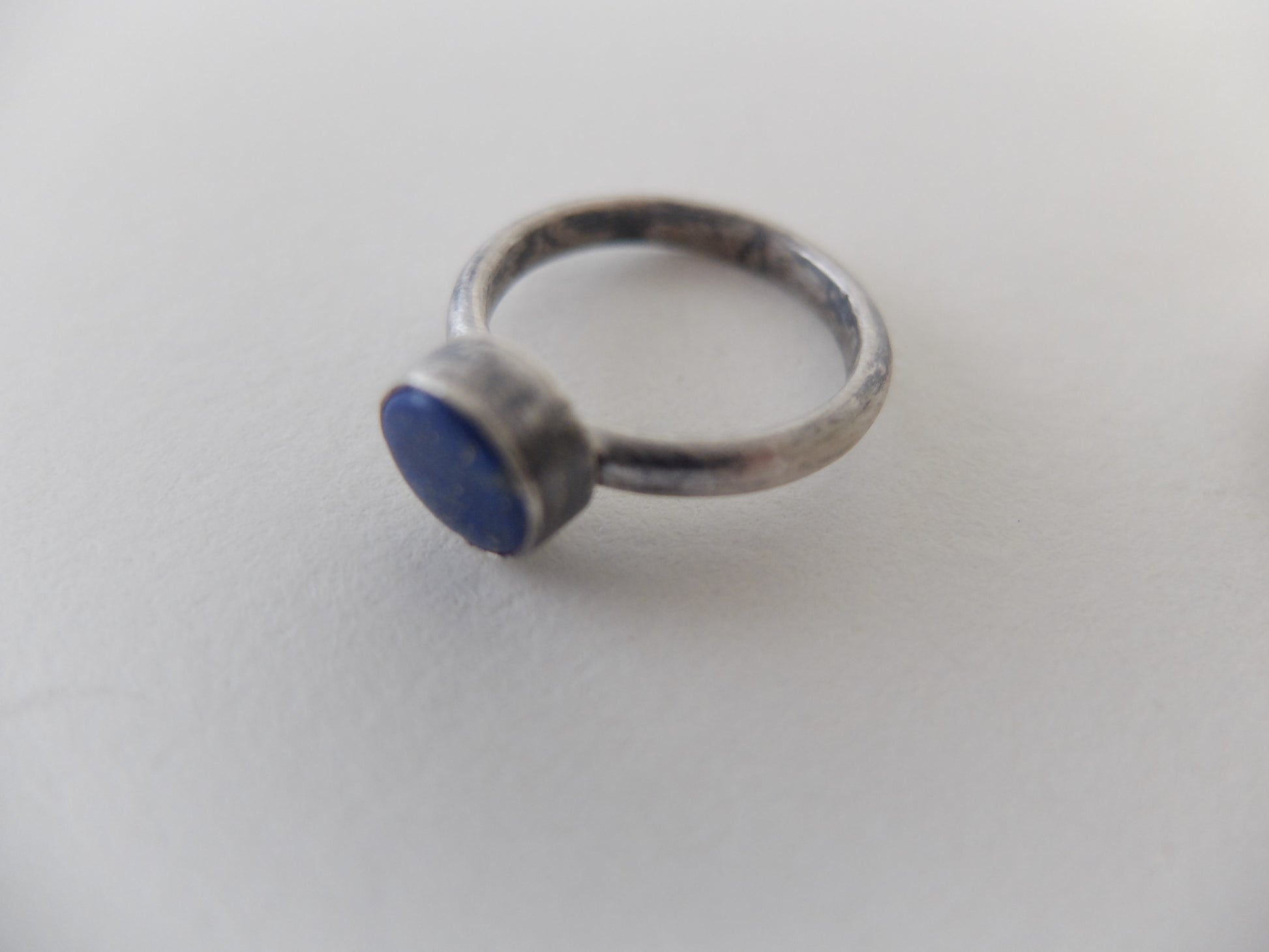 Silver ring with a blue stone on a light gray background