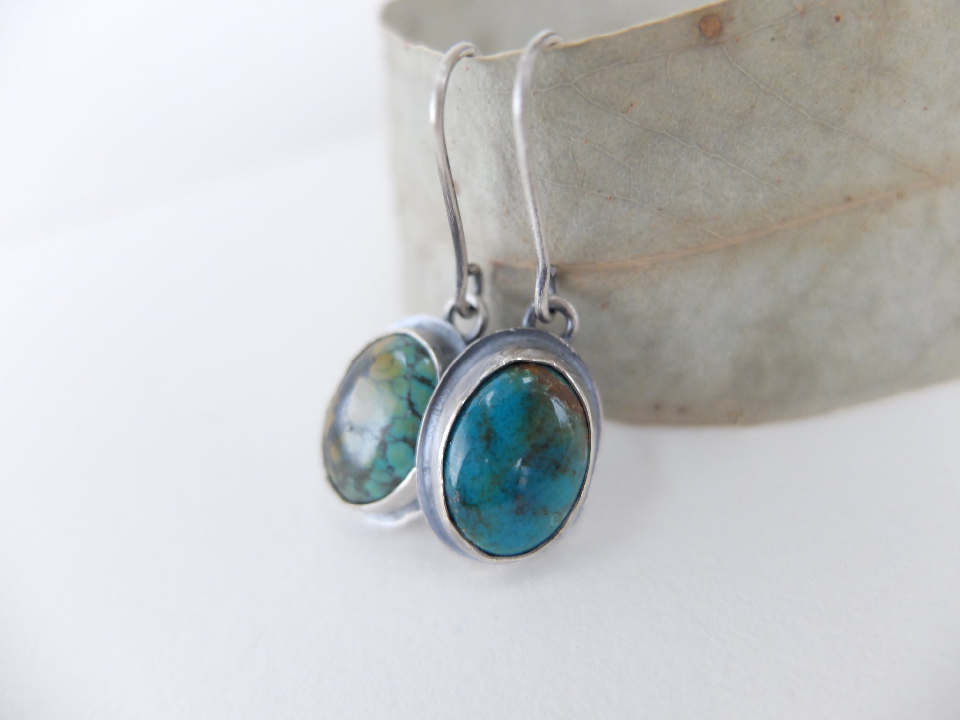 Turquoise stone earrings on silver hooks against a white background