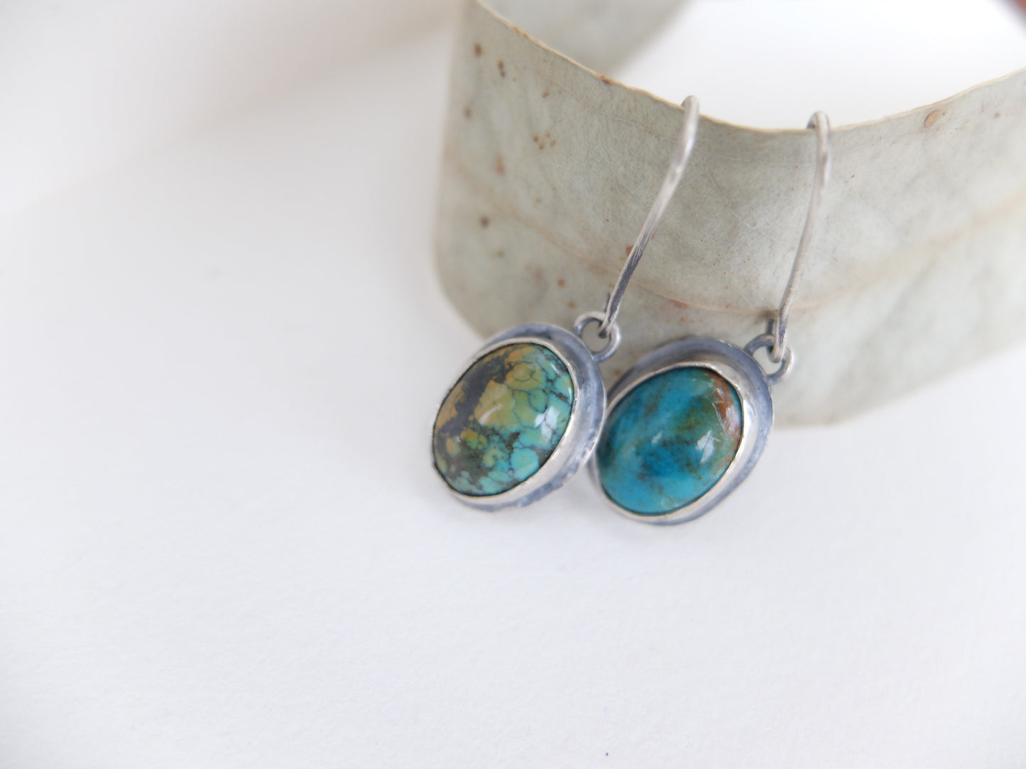Pair of silver earrings with turquoise stones on a white background