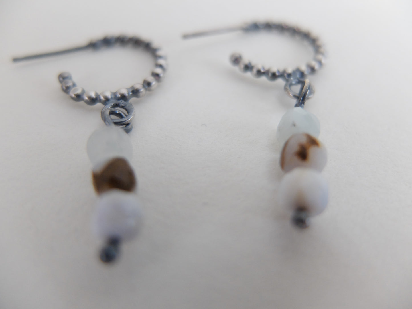 Pair of earrings with white and brown beads on a light background