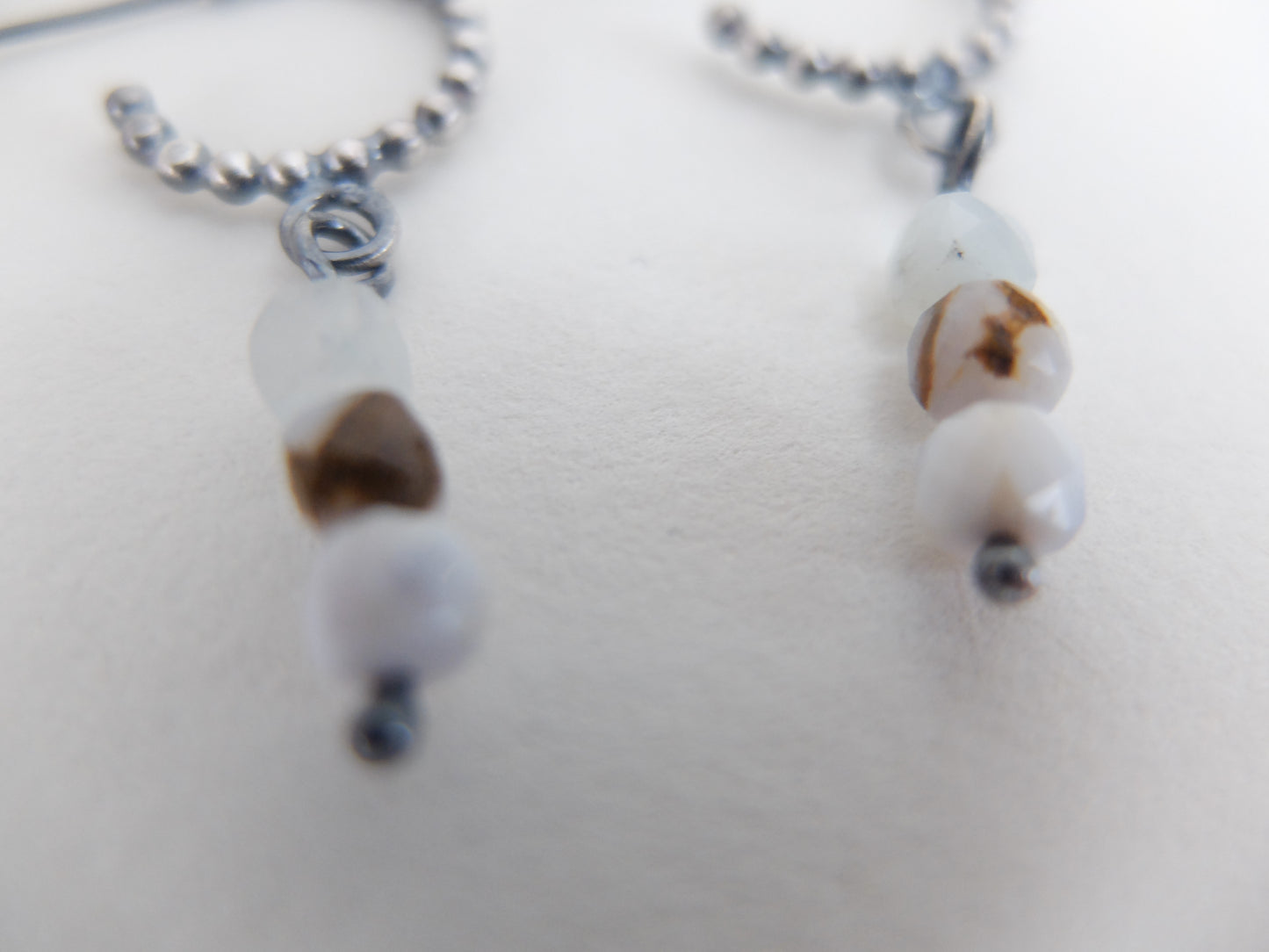 Close-up of earrings with white and brown beads on a light background