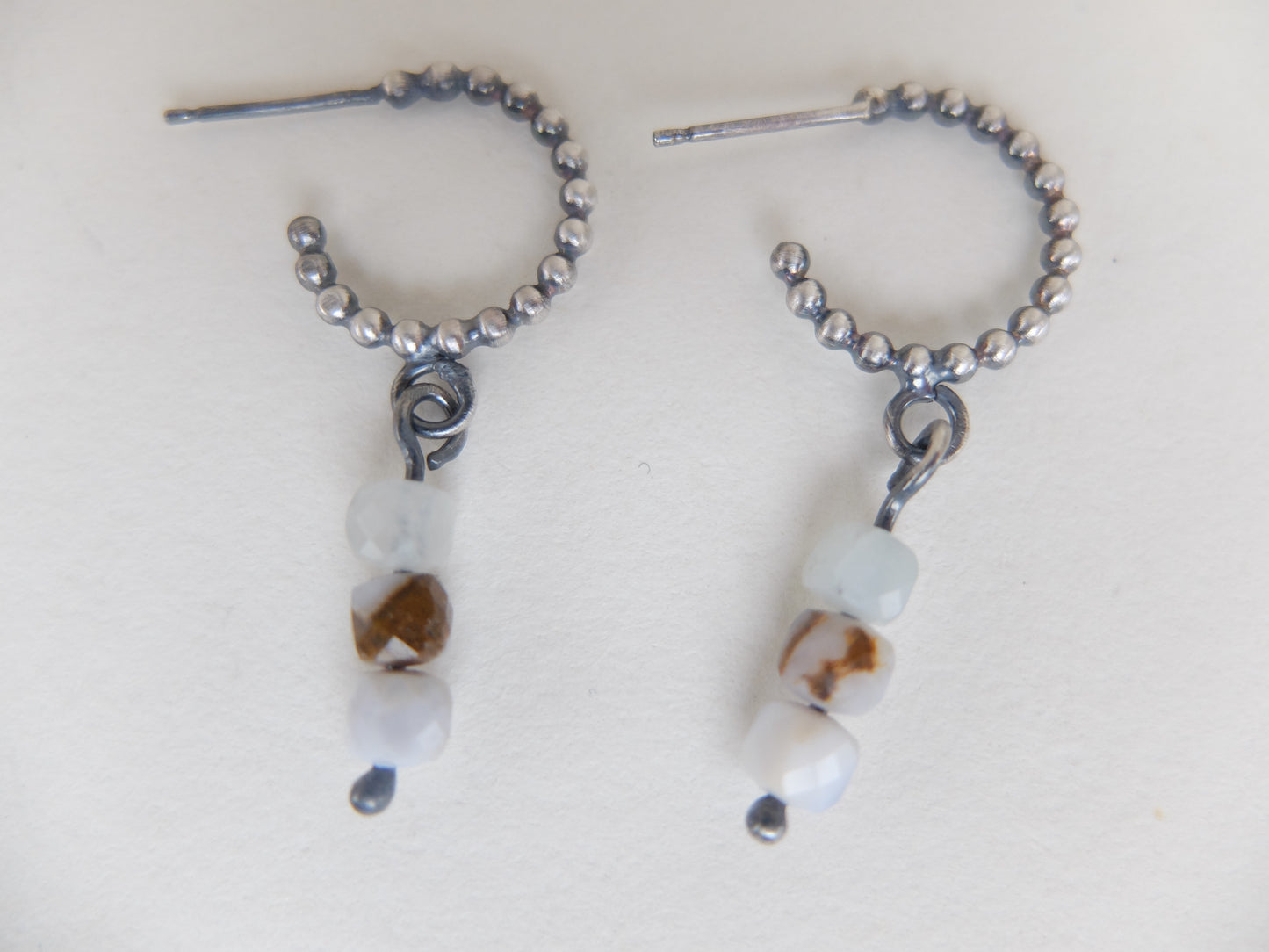 Pair of beaded earrings with natural stone-like beads on a white background