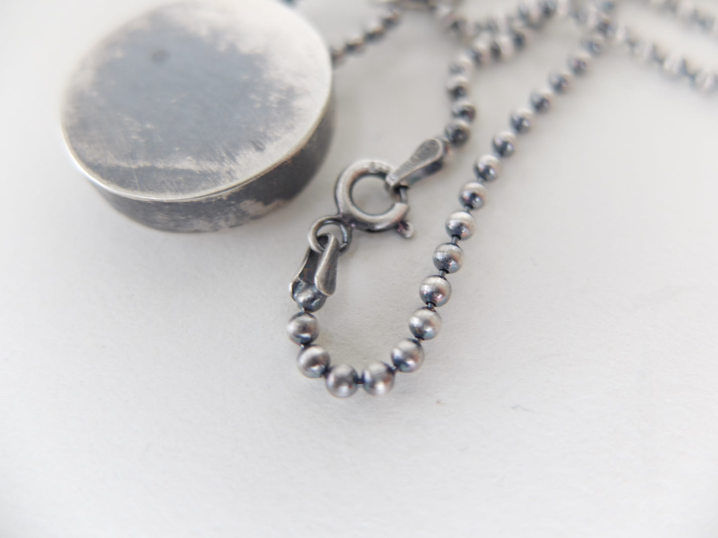 Close-up of a silver beaded necklace with clasp on a white background