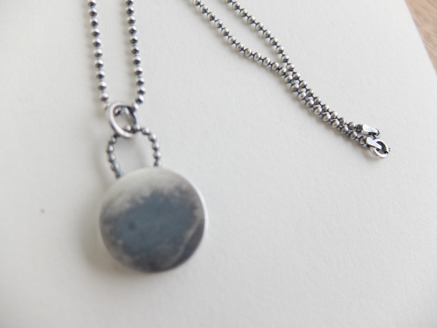 Necklace with a round, gray pendant on a light background