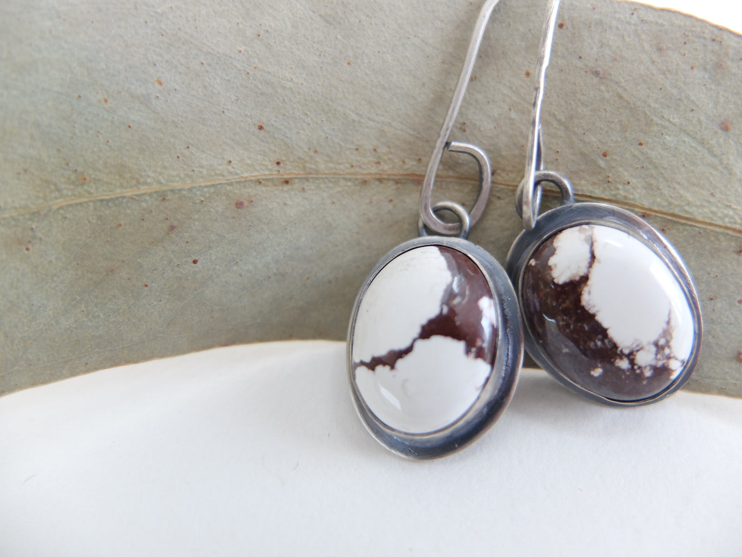 Pair of earrings with marbled design on a neutral background