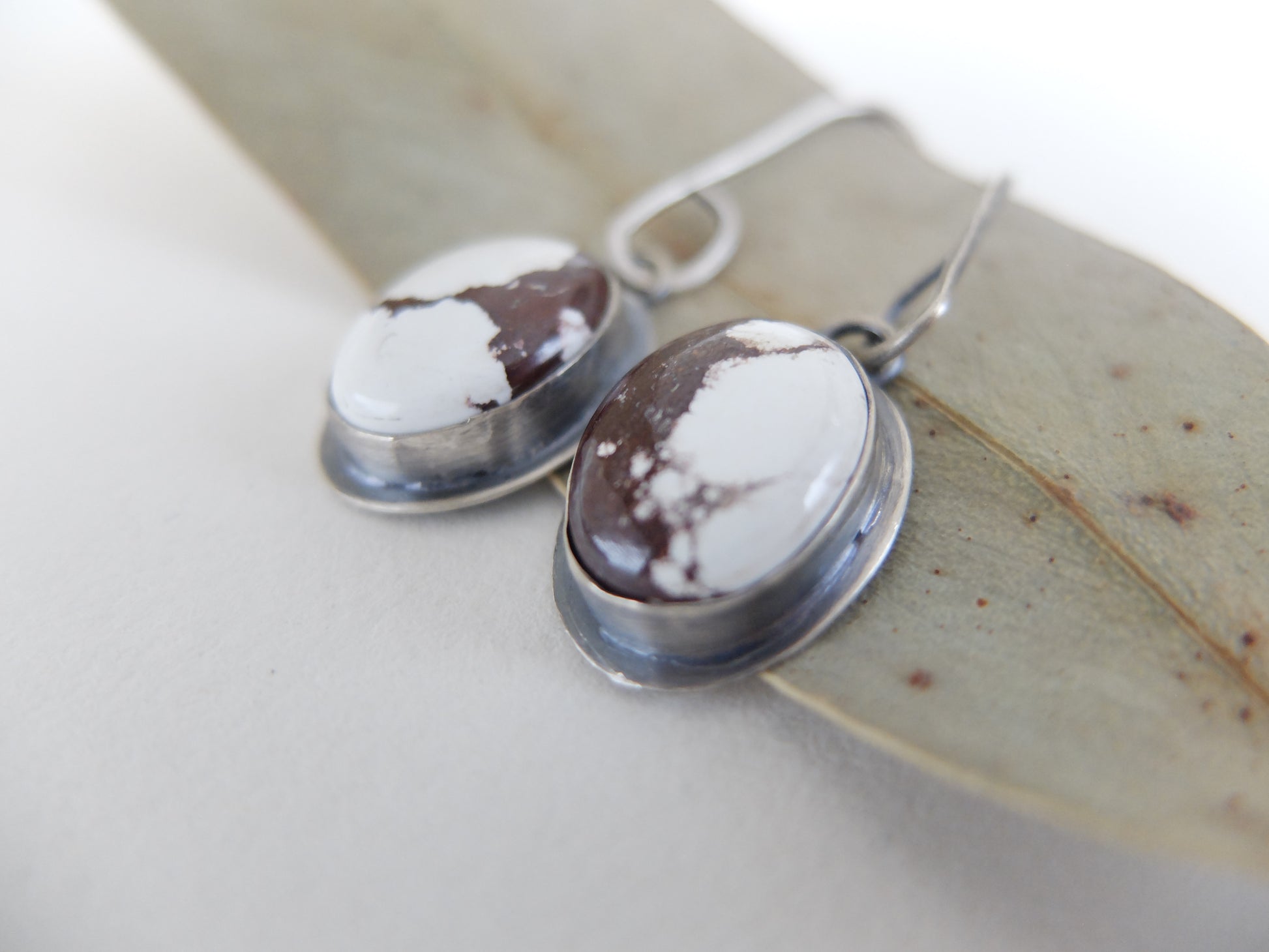 Pair of earrings with brown and white stones on a leaf