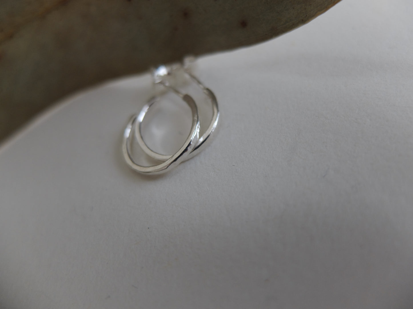 Silver earring hoop on a light grey background