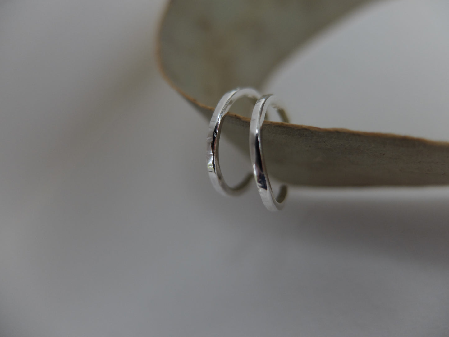 Two silver hoop earrings on a light wooden surface