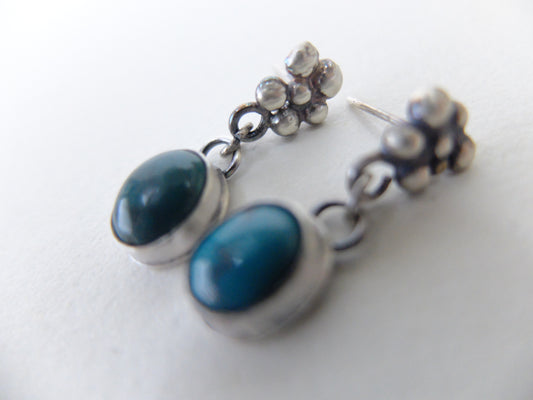 Pair of earrings with blue stones and silver accents on a white background