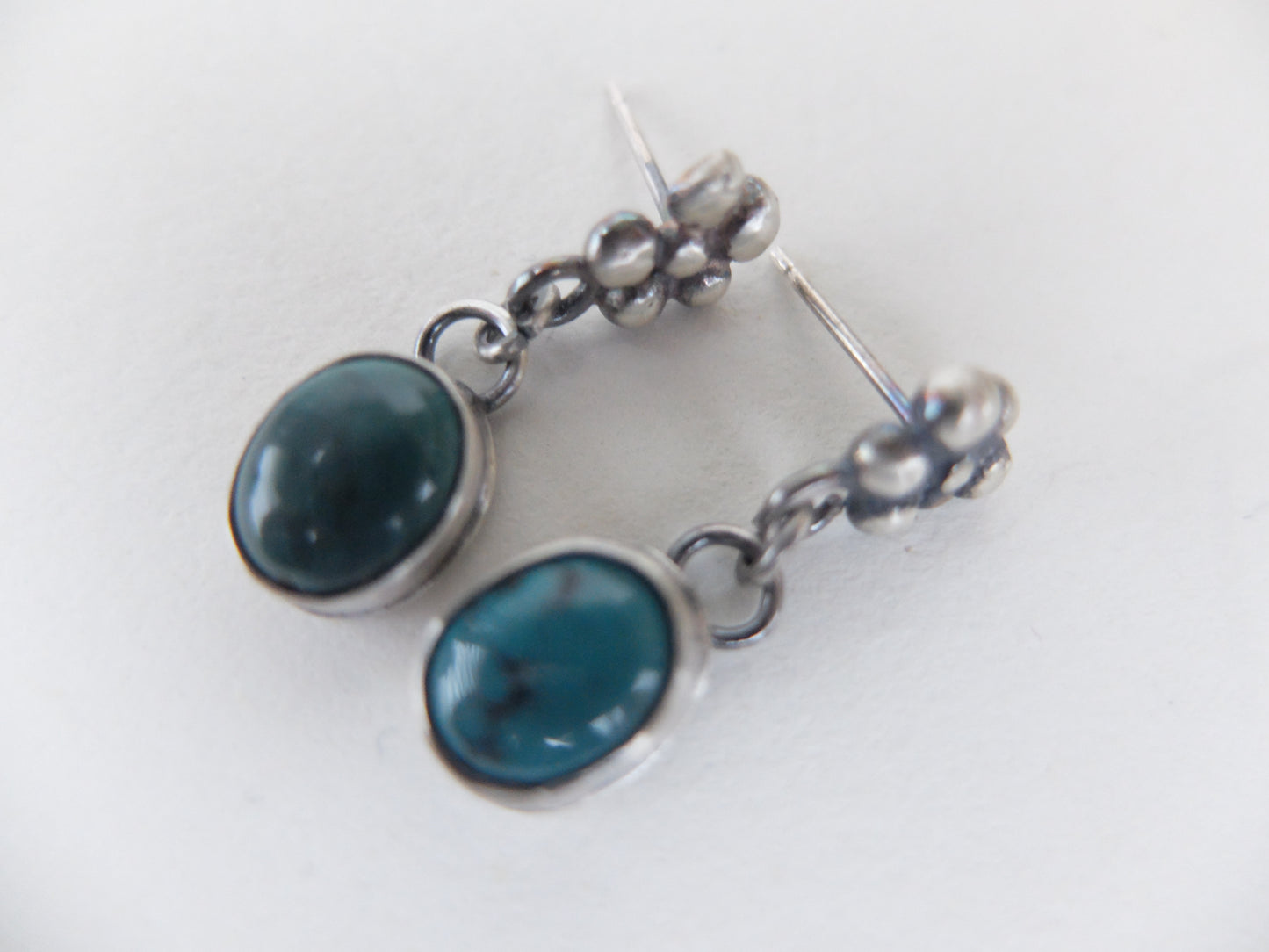 Silver earrings with blue stones on a white background