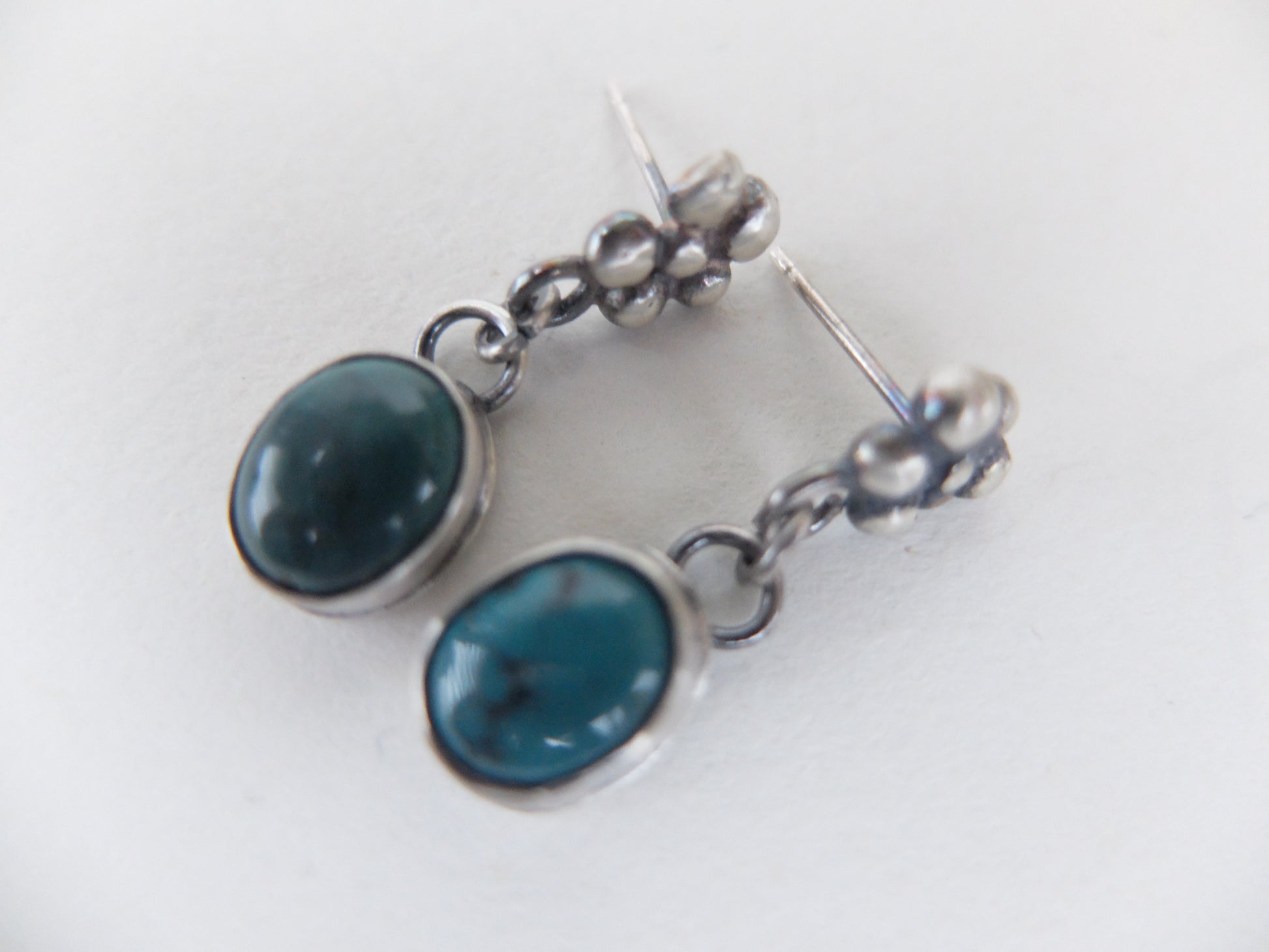 Silver earrings with blue stones on a white background