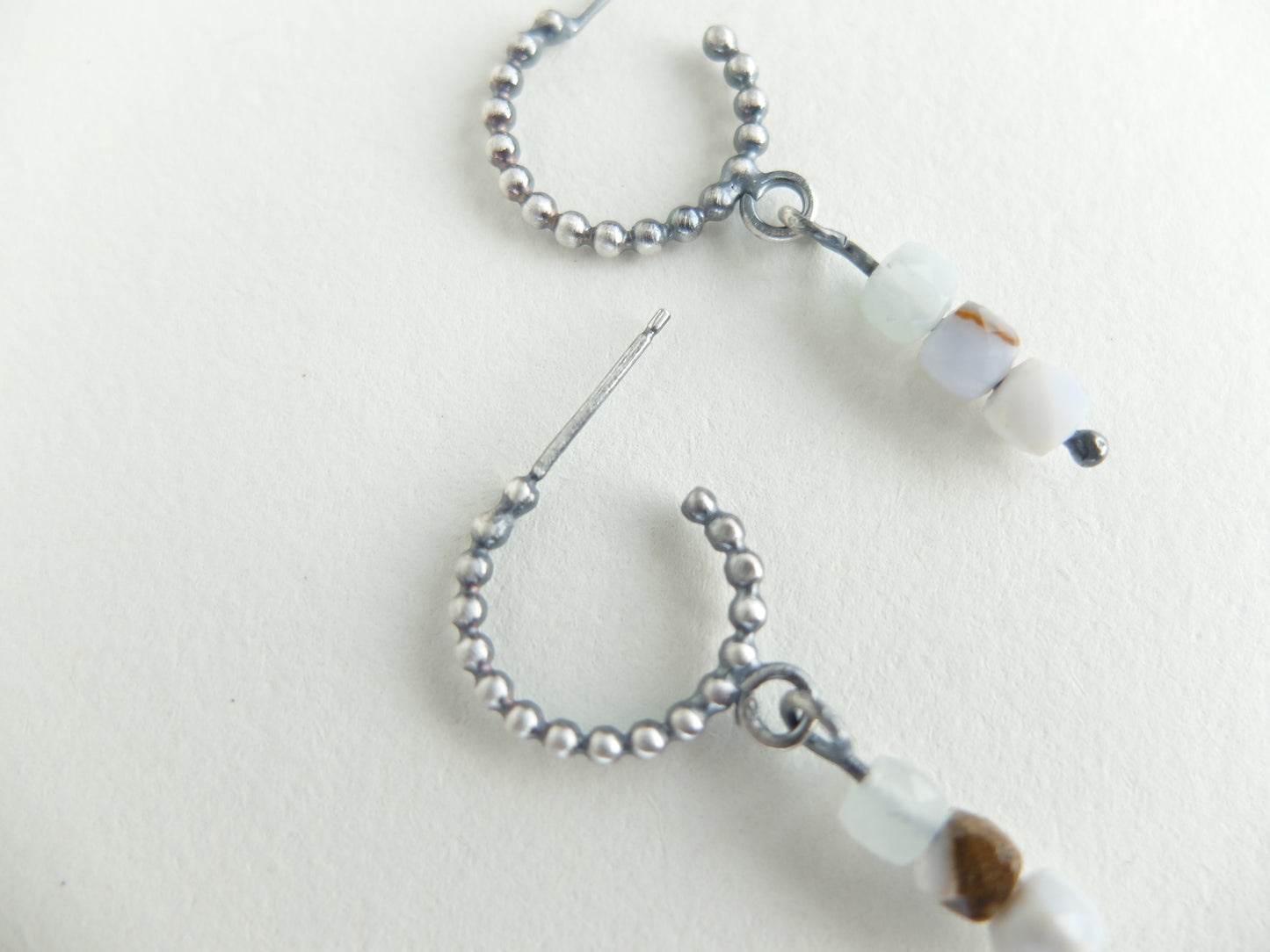Close-up of a beaded earring with a needle on a light background