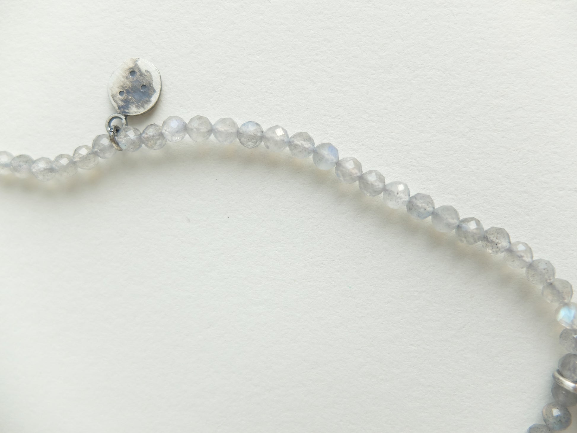 Silver bracelet with small beads on a light gray background