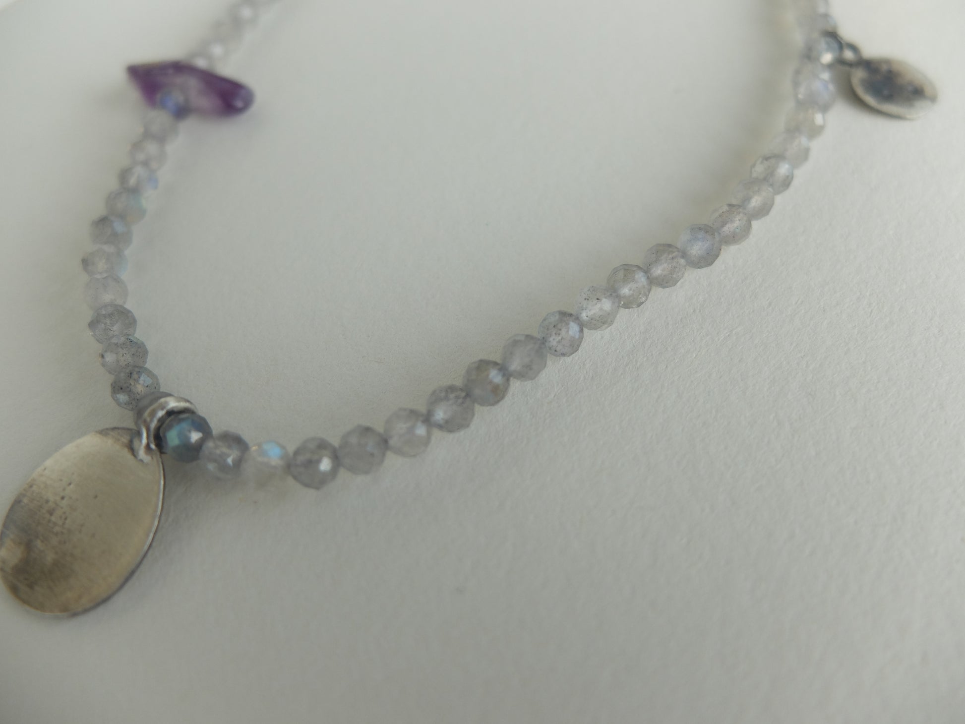 Necklace with silver pendants and beads on a light gray background