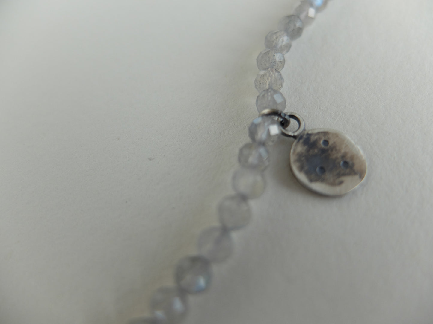 Necklace with small round beads and a round charm on a light background