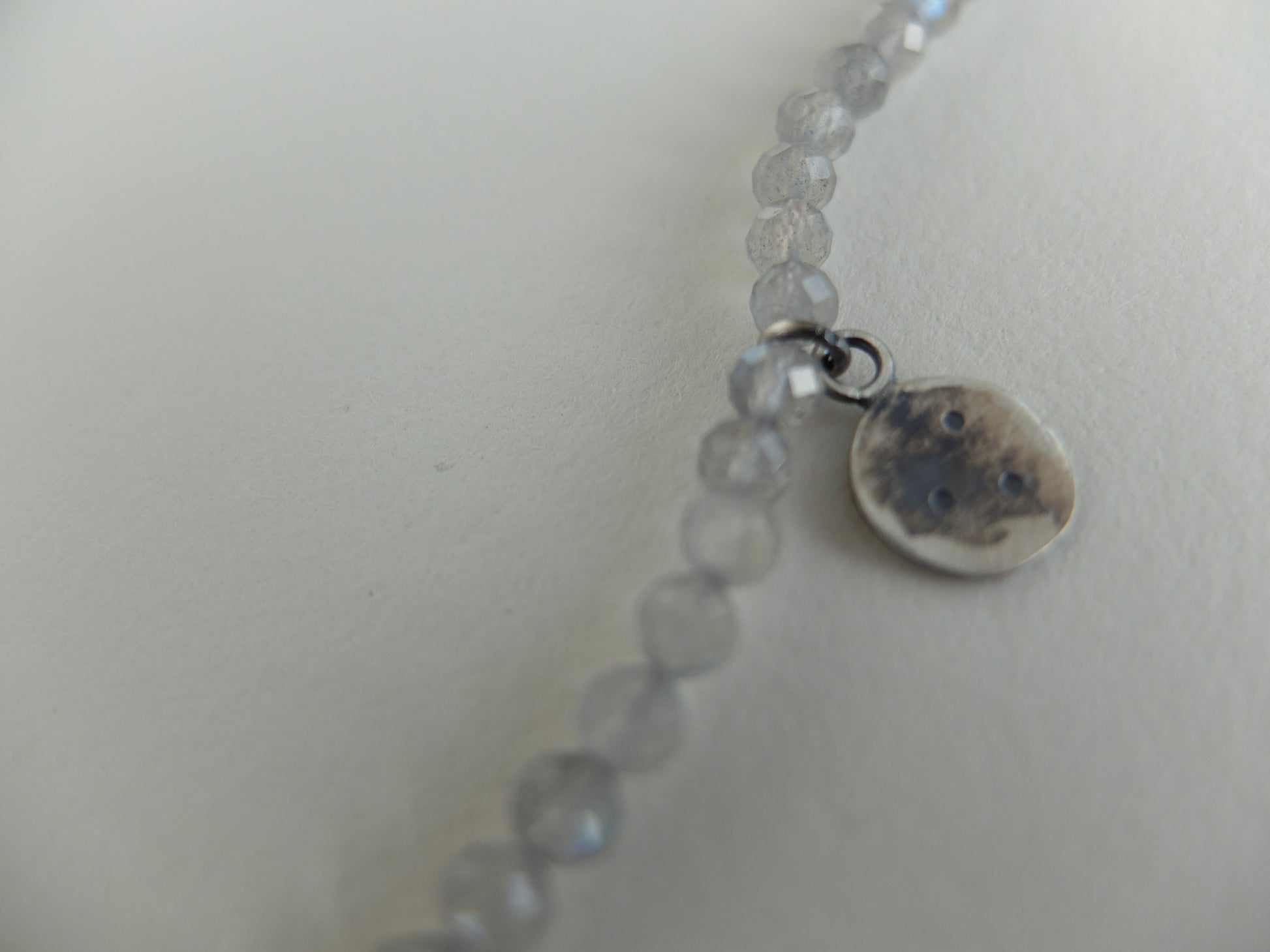 Necklace with small round beads and a round charm on a light background