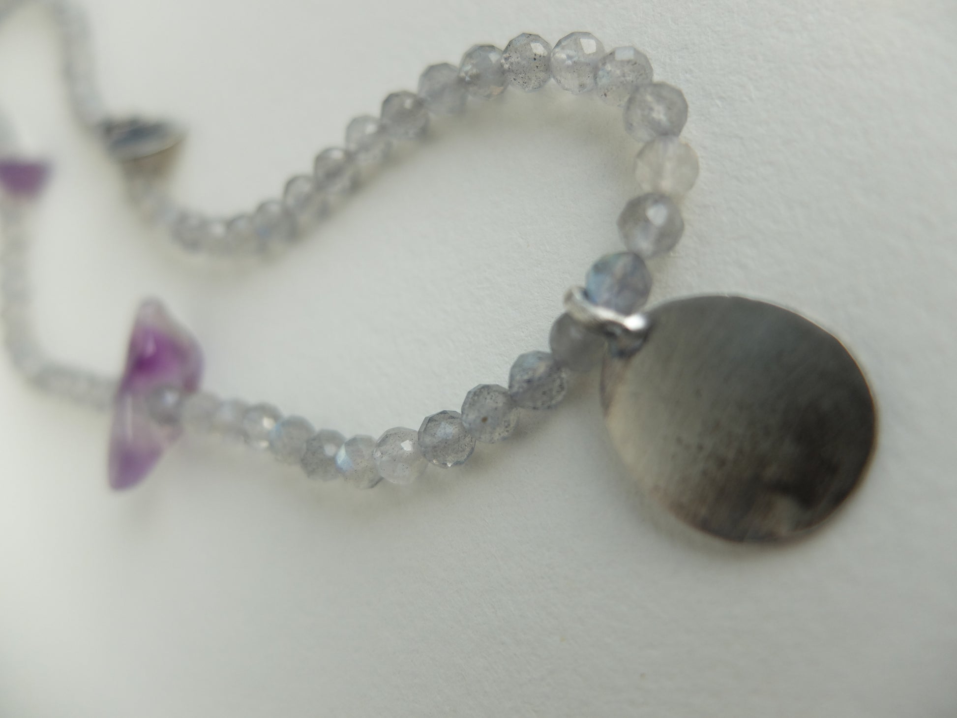 Necklace with beaded chain and round pendant on a light background
