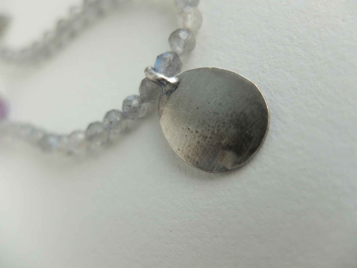 Necklace with a round pendant and beaded chain on a light background