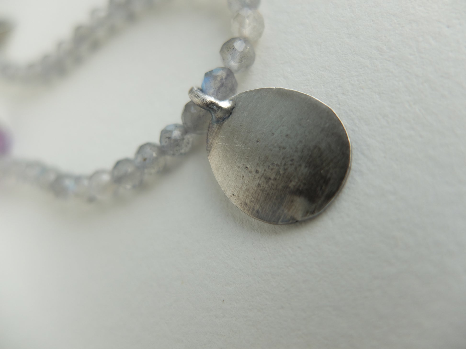 Necklace with a round pendant and beaded chain on a light background