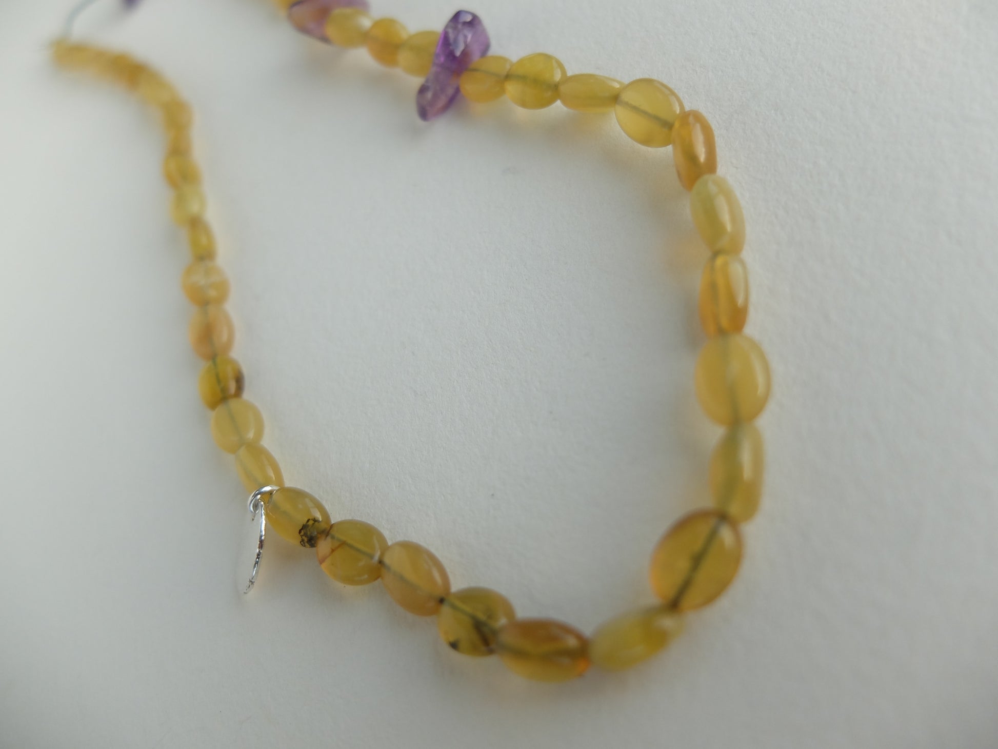 Beaded necklace with yellow opals and amethysts beads on a white background