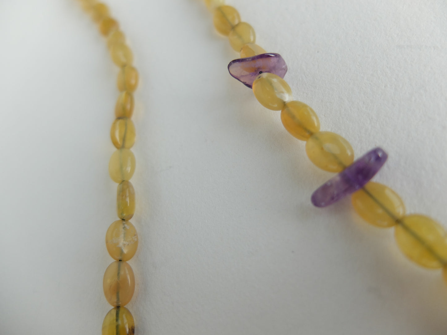 Close-up of a necklace with yellow and purple beads on a white background
