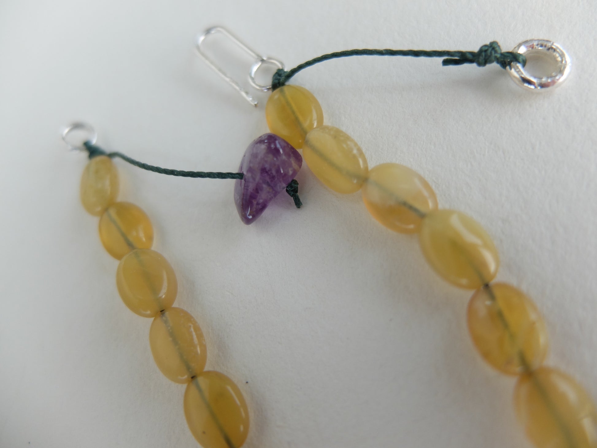 Close-up of a necklace with yellow beads and a purple bead on a white background