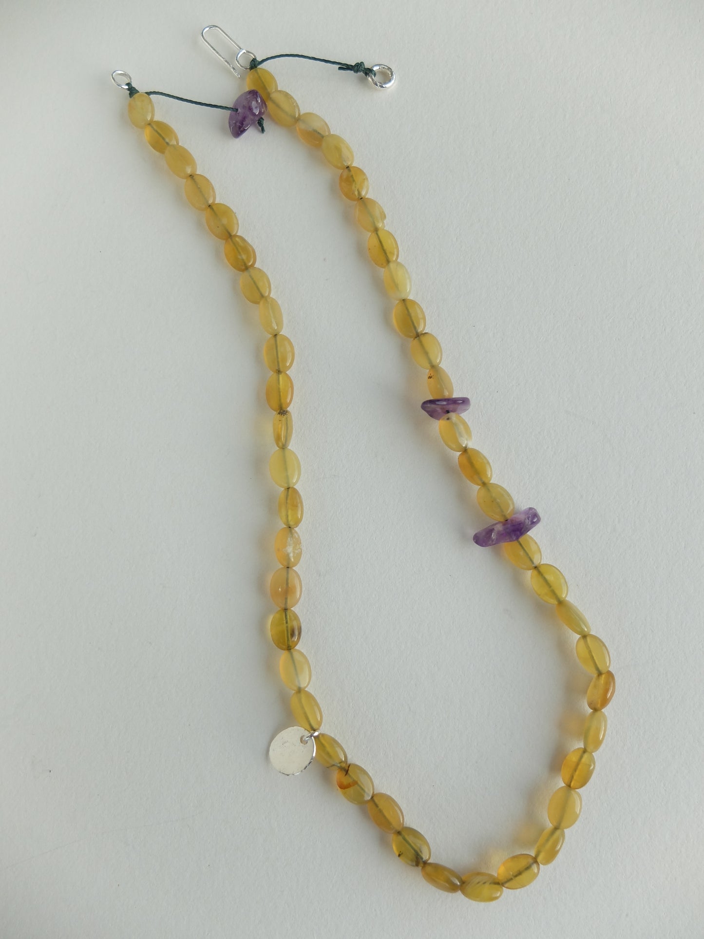 Beaded necklace with yellow beads and purple accents on a white background