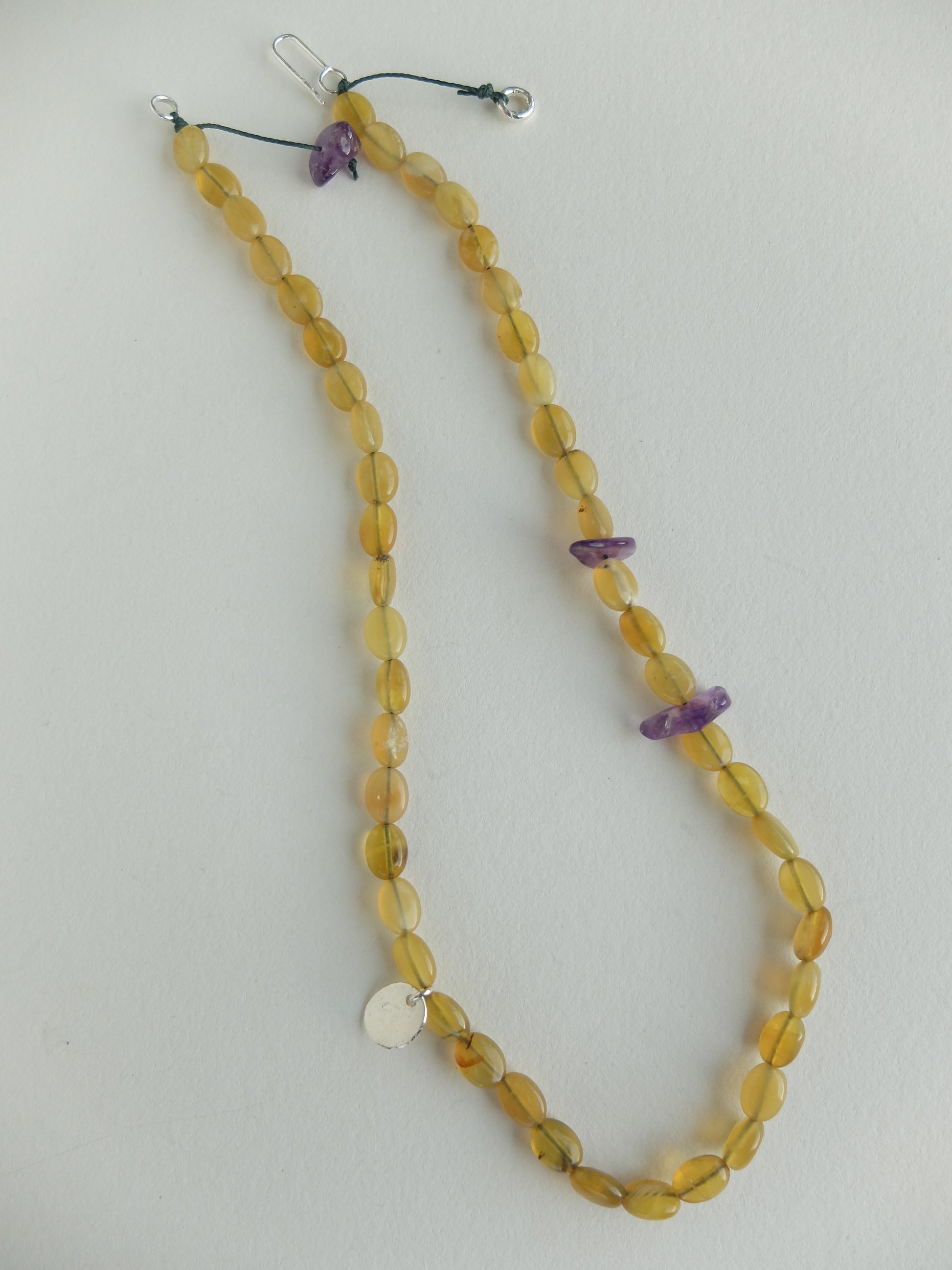 Beaded necklace with yellow beads and purple accents on a white background