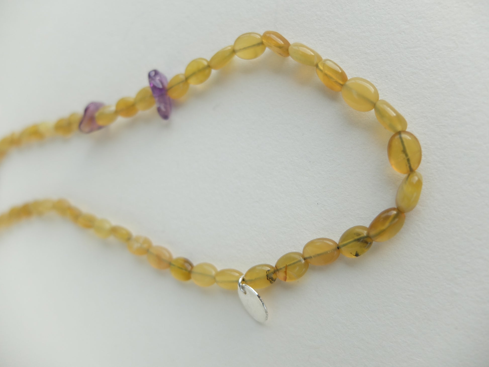 Beaded necklace with yellow and purple beads on a white background