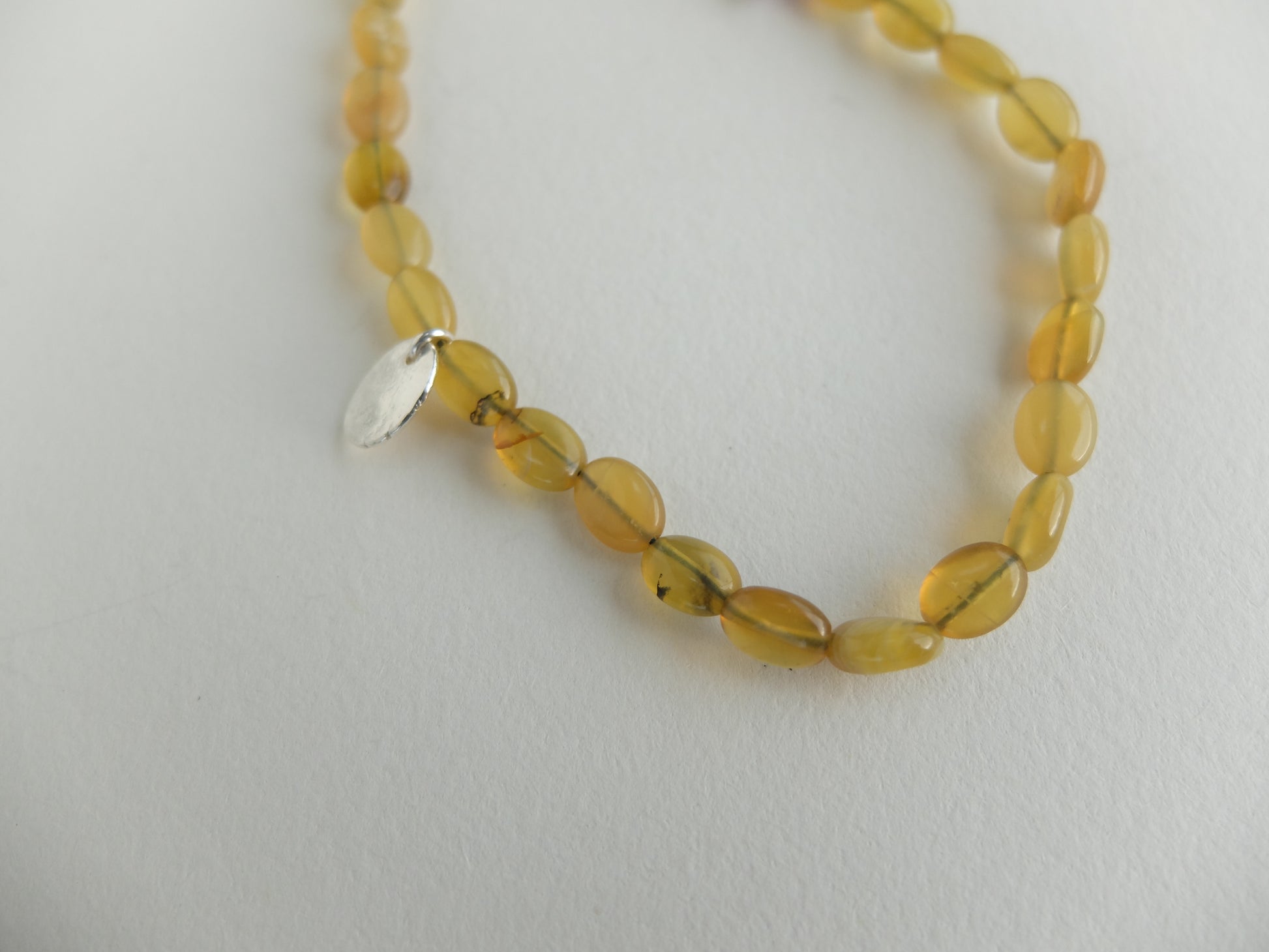 Yellow beaded necklace with a silver clasp on a light gray background