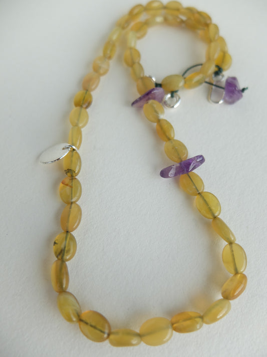 Beaded necklace with yellow beads and purple accents on a white background