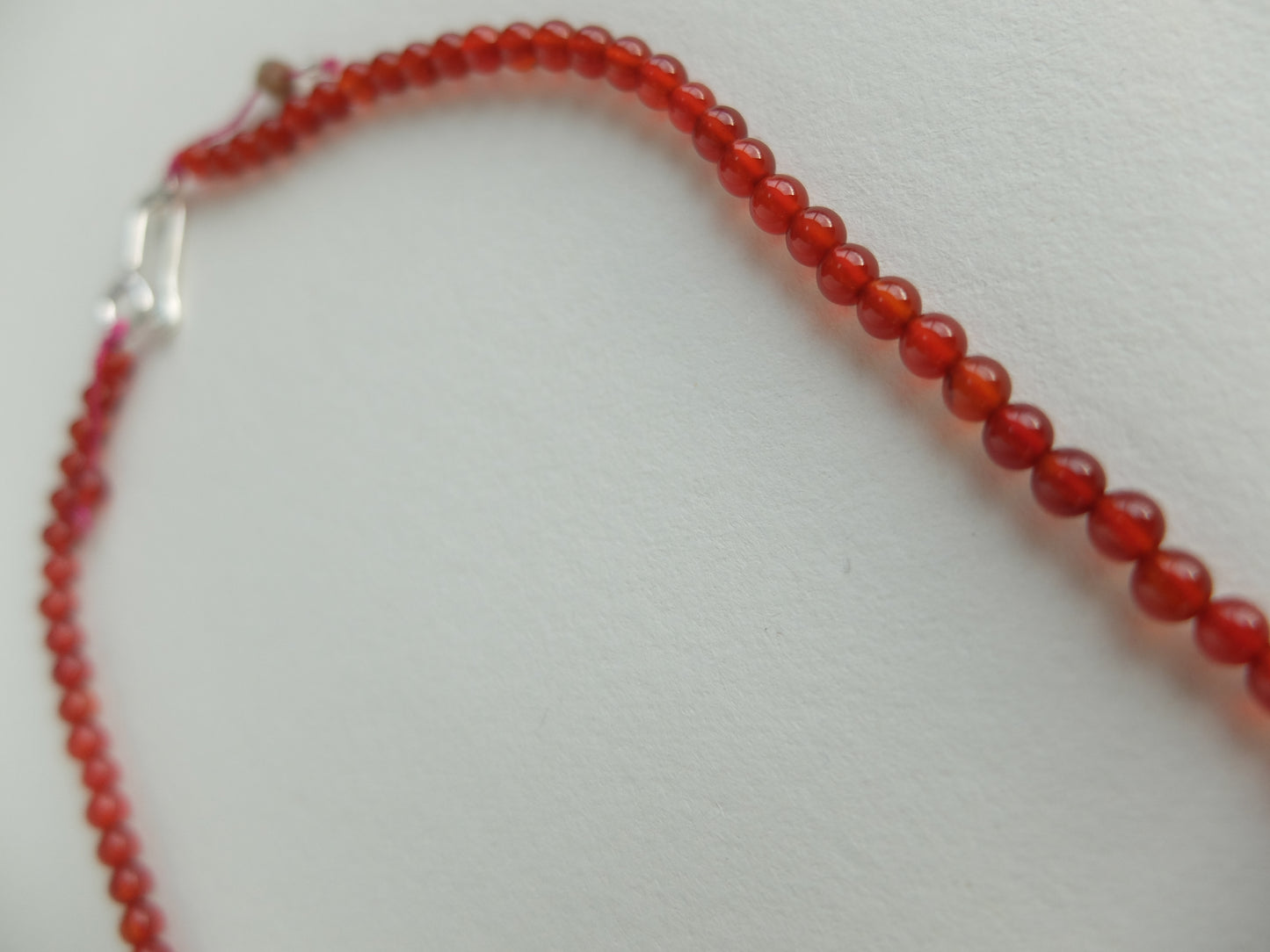 Red beaded necklace with a silver clasp on a light gray background
