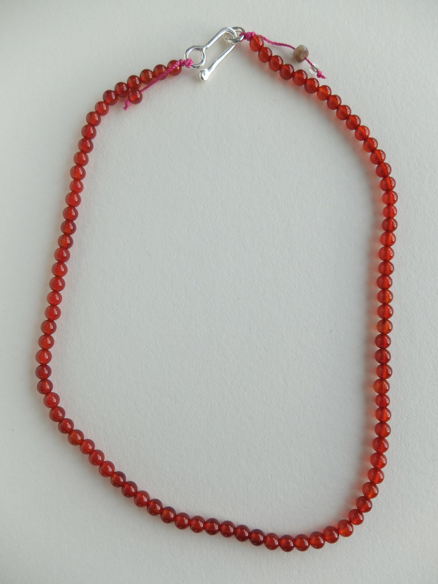 Red beaded necklace with a silver clasp on a light gray background
