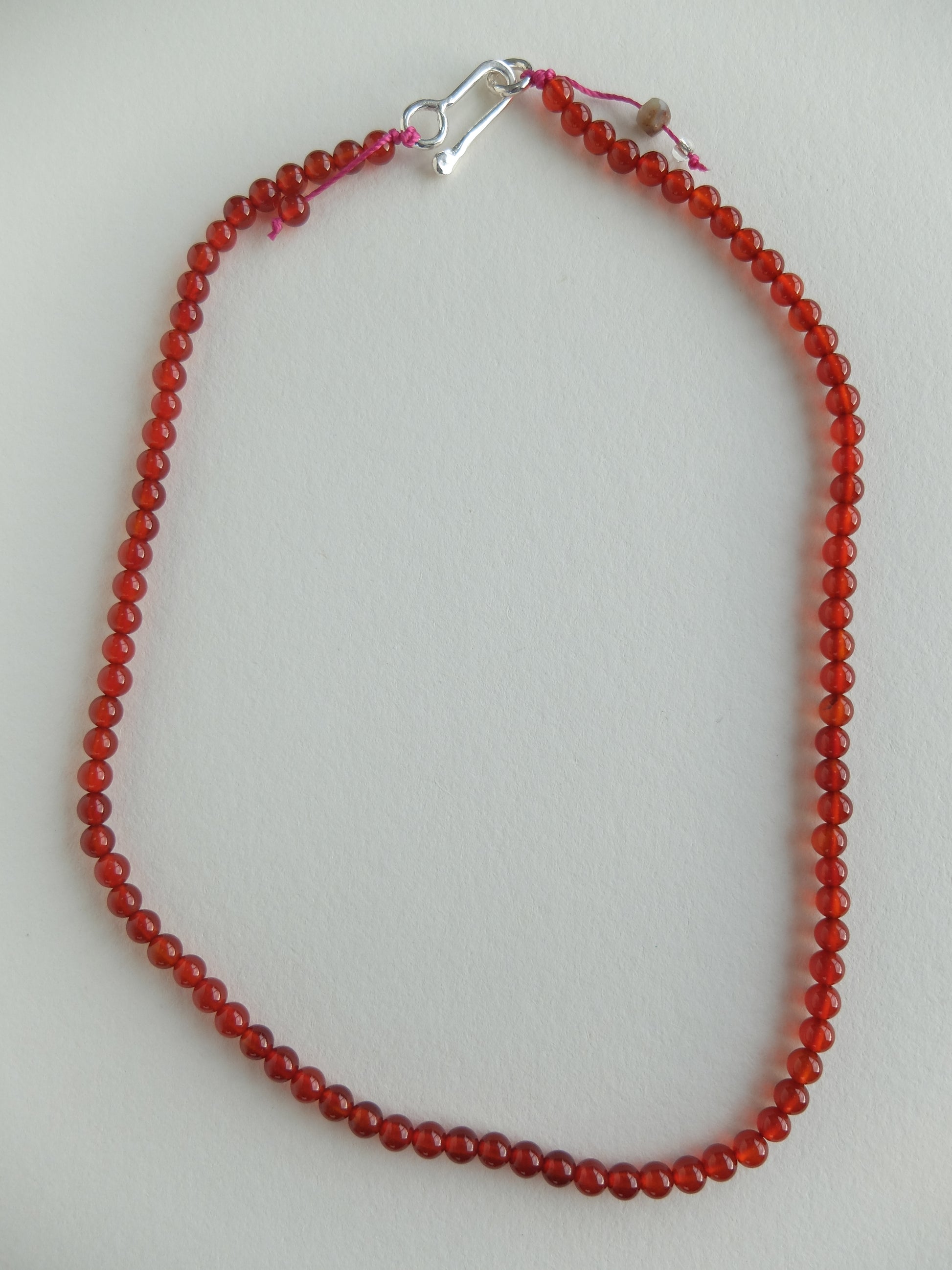 Red beaded necklace with a silver clasp on a light gray background