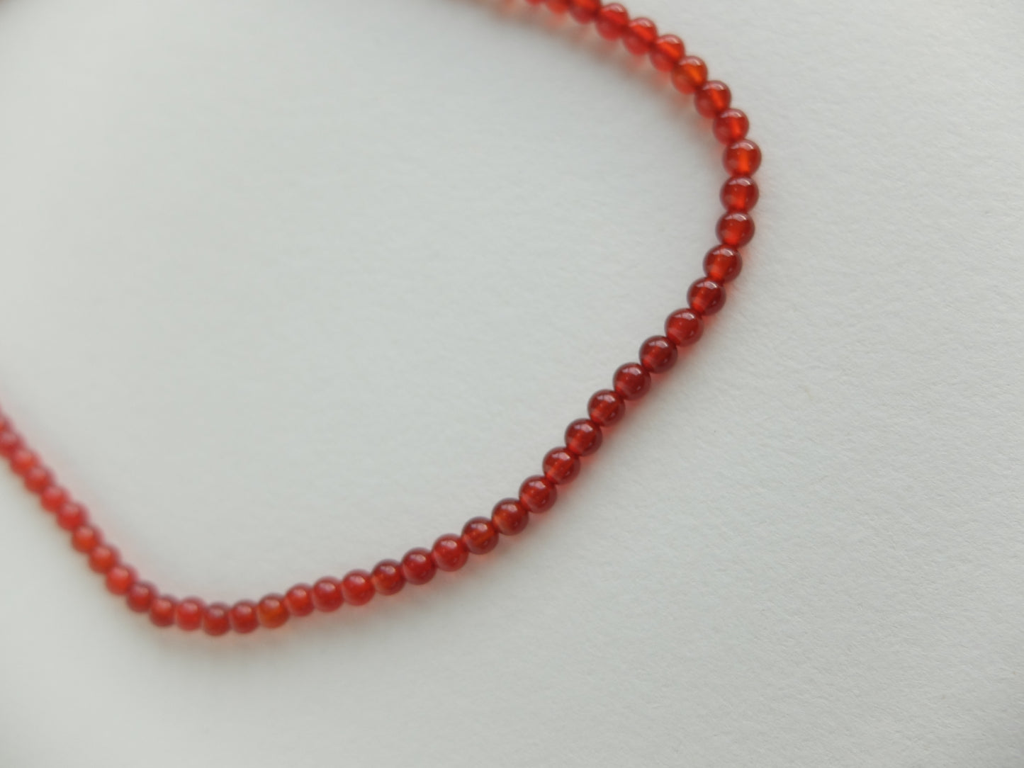 Red beaded necklace on a light gray background