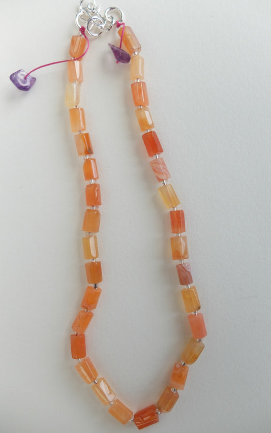 Necklace with orange red agate beads on a white background