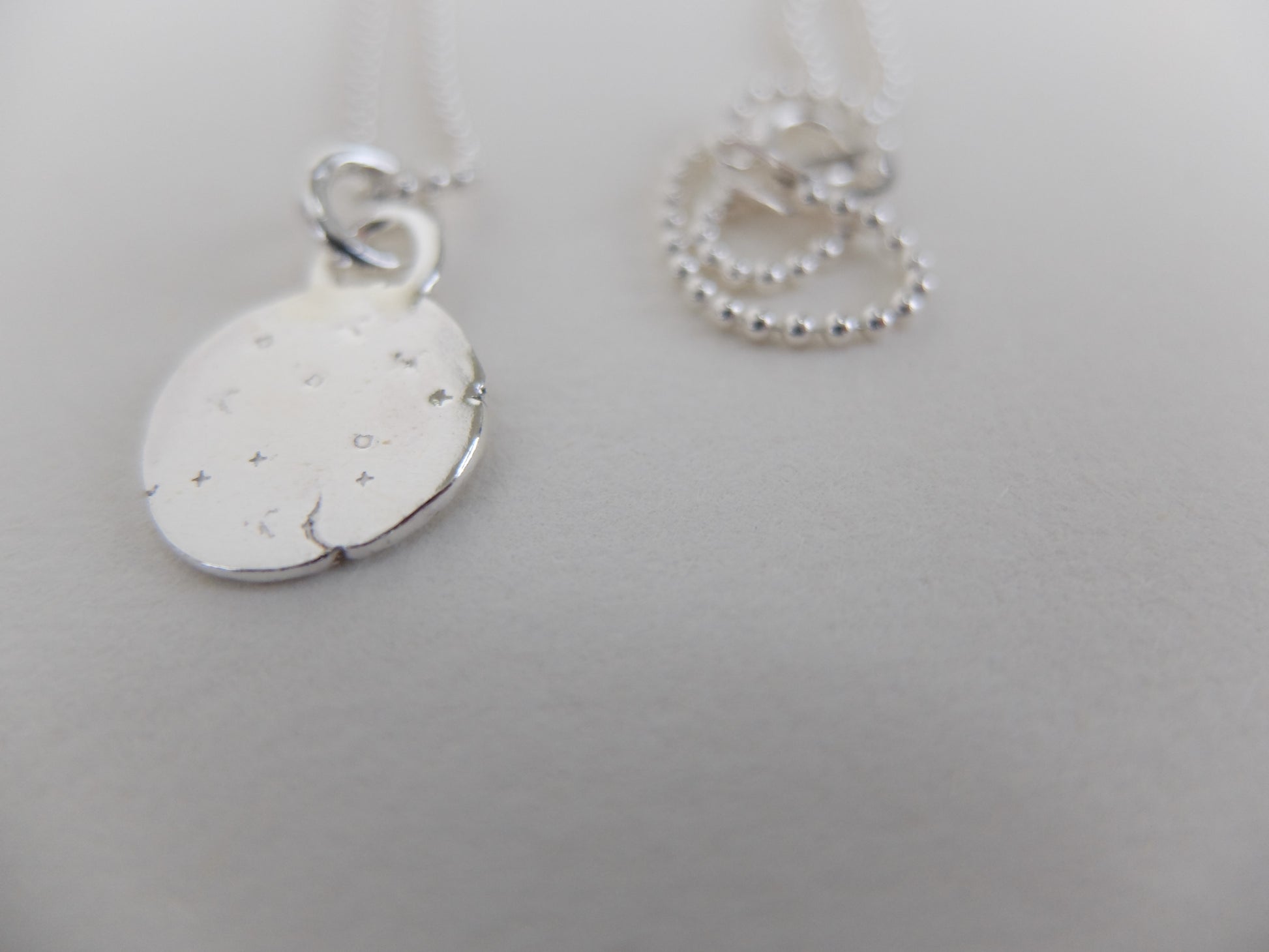 Silver necklace with a round pendant on a light gray background