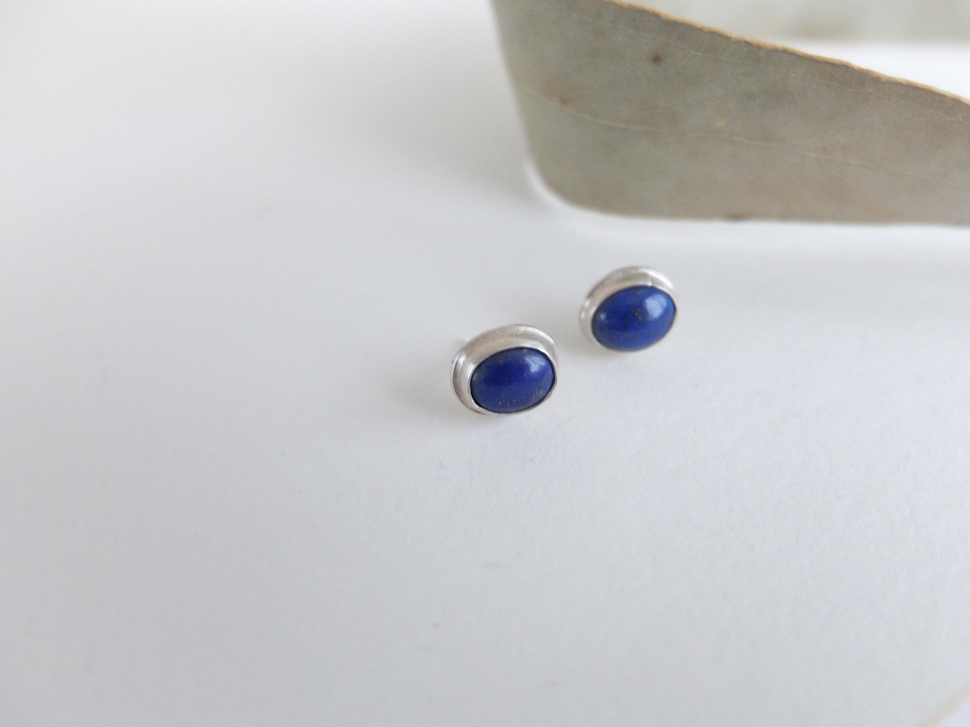 Silver earrings with blue stones on a white surface
