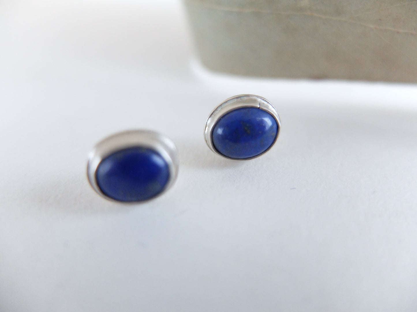 Pair of blue oval earrings on a white surface